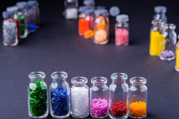 Varied colors beads in transparent bottles row dark background