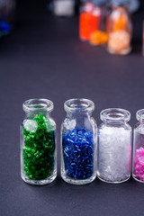 Varied colors beads in transparent bottles row dark background