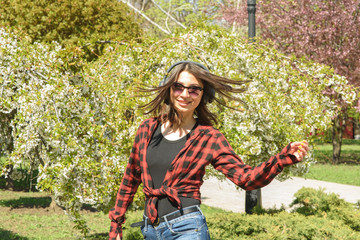 Happy girl listening to music on headphones and dancing in the park