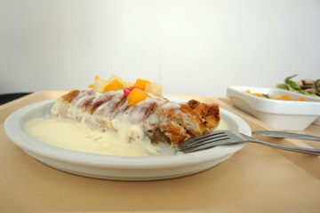 Delicious apple strudel with custard and fruit salad in a canteen in Germany