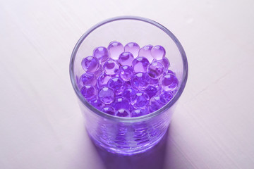 Purple marbles in drinking transparent glass white background
