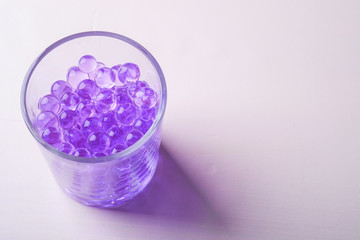 Purple marbles in drinking transparent glass white background
