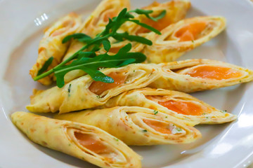pancakes with red fish on a plate. Salmon pancakes on a table in a restaurant