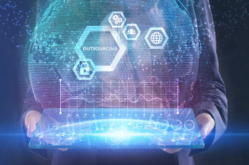 The concept of business, technology, the Internet and the network. A young entrepreneur working on a virtual screen of the future and sees the inscription: Outsourcing