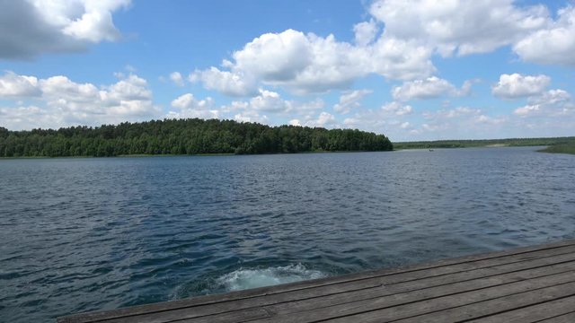 Mann springt von einem Holzsteg in den See