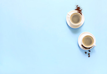 Two cups of espresso . Coffee beans, ground coffee on blue background