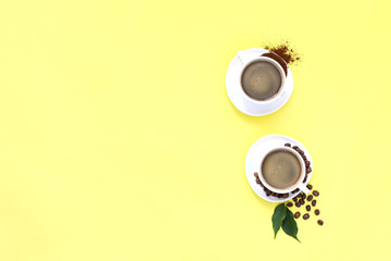 Two cups of espresso . Coffee beans, ground coffee on yellow background