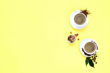 Two cups of espresso . Coffee beans, ground coffee on yellow background