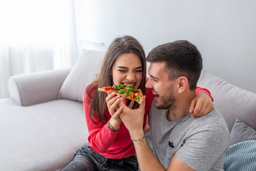 Close up of a young beautiful couple sharing pizza cut. Beautiful young couple eating pizza,talking...