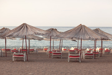 Sun loungers with an umbrella on the beach overlooking the sea, summer concept