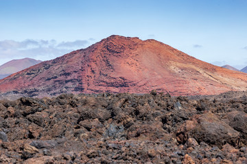 Red volcano near Los Hervideros caves in Lanzarote, Canary Islands. Spain