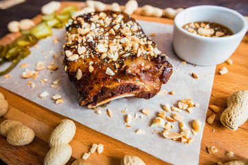 Close up board with pork ribs grilled with BBQ sauce, peanuts and jalapeno