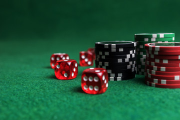 Casino game. Poker chips and red dice on green table