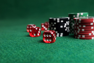 Casino game. Poker chips and red dice on green table