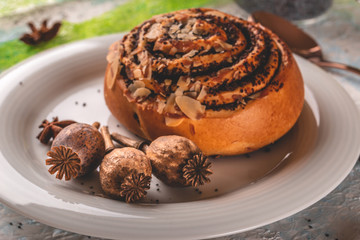 Few poppy heads on white plate with sweet baked bun and spices
