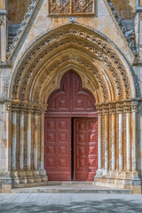 Fototapeta na wymiar Detail view at the frontal gate and door of the ornate Gothic exterior facade of the Monastery of Batalha literally the Monastery of the Battle, in Leiria, Portugal