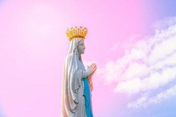 Virgin Mary statue on the pink sky background. Statue of Our Lady, fragment. Lourdes, France