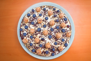 Vollkornkuchen mit Blaubeeren und Nusskugeln dekoriert auf einer Porzellanplatte