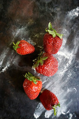 Ripe, red strawberries with powered icing sugar on a dark background . Top view with copy space