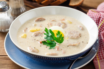 Traditional polish soup Zurek on wooden table. Selective focus.
