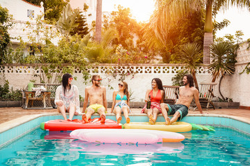 Group of happy friends relaxing in swimming pool - Young people having fun in exclusive summer...