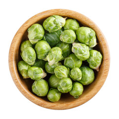 Fresh raw organic brussels sprouts in wooden bowl isolated on white. Top view, close-up.