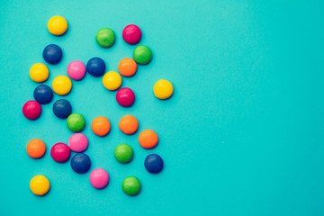 close up of chocolate egg and candy drops on blue background