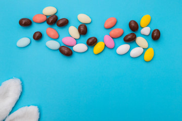 close up of chocolate egg and candy drops on blue background