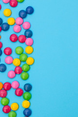 close up of chocolate egg and candy drops on blue background