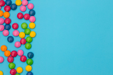 close up of chocolate egg and candy drops on blue background