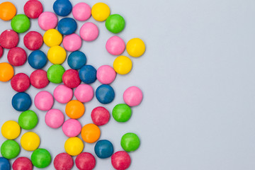 close up of chocolate egg and candy drops on gray background