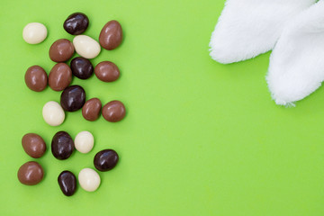 close up of chocolate egg and candy drops on green background