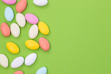 close up of chocolate egg and candy drops on green background