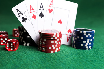 Poker chips, playing cards and red dice on green table. Casino game