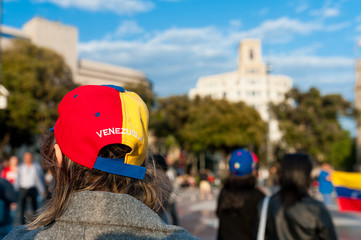 old woman wearing hat with venezuelan flag and country name in Barcelona city main square during...
