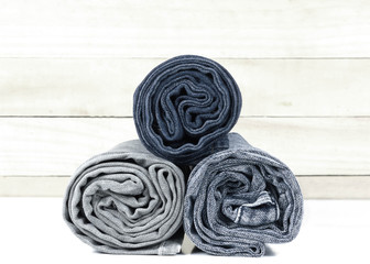  jeans stacked on wooden floor. blank background for design and text input.