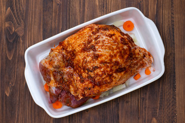 raw turkey leg with spices and vegetables on dish on wooden background
