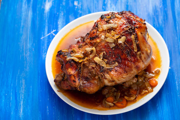 baked turkey leg with vegetables and herbs on white dish