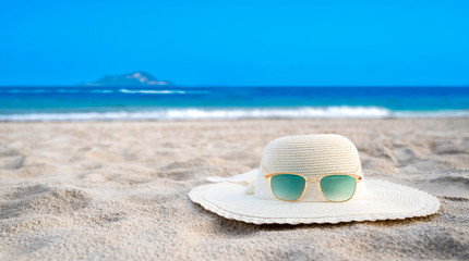 Hats and glasses are located on the sea blue sea beaches on a clear day