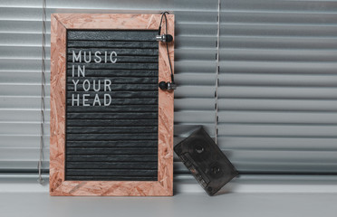 Letter board with the inscription music in your head in white letters on black.Headphones and audio...