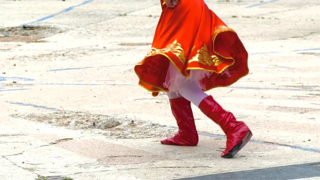 Girl dancing folk dance in red costume and red boots