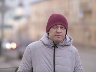 Portrait of a young man on a blurred background of the street, looking at the camera