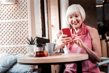 Cheerful old lady comfortably sitting in a cafe