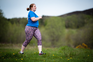 Woman in 30s exercising and keeping fit by running in a park