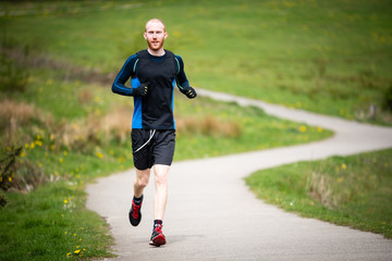 Young man in mid 20s exercising and keeping fit by running in a park