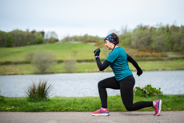 Senior woman in 50s warming up before  exercising and keeping fit by running in a park