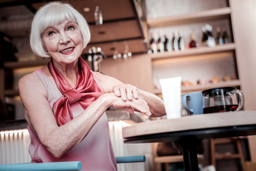 Short-haired senior woman with bright makeup caring her hand