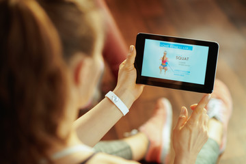 young sports woman using home workout trainer app in tablet PC