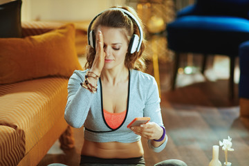 young woman watching yoga tutorial on internet via smartphone