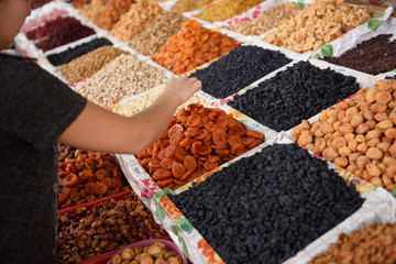 Woman selecting dried fruits and nuts on display at Shymkent Central Market Kazakhstan